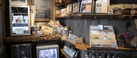 Un café con decoración rústica, que presenta un menú en pizarra, diversas opciones de café y té, y una exhibición de botellas de agua reutilizables.