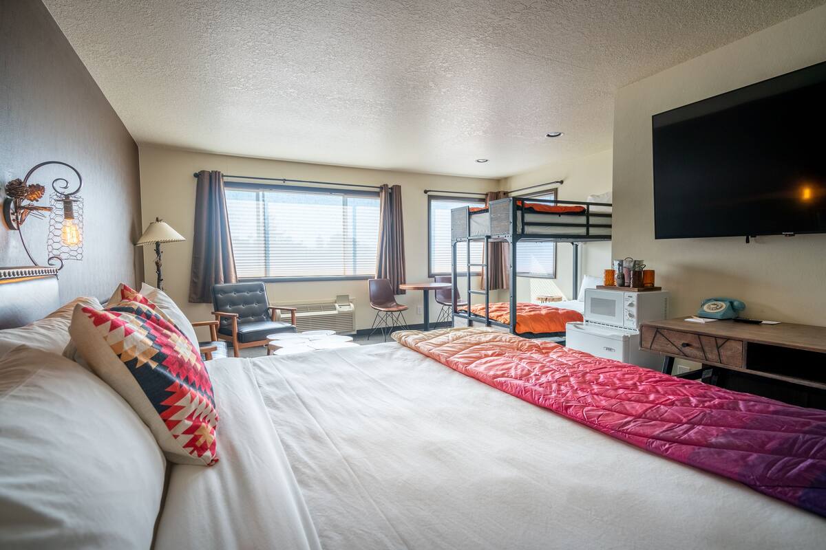 Habitación de hotel con una cama grande, un escritorio con computadora, un televisor y una cama nido.