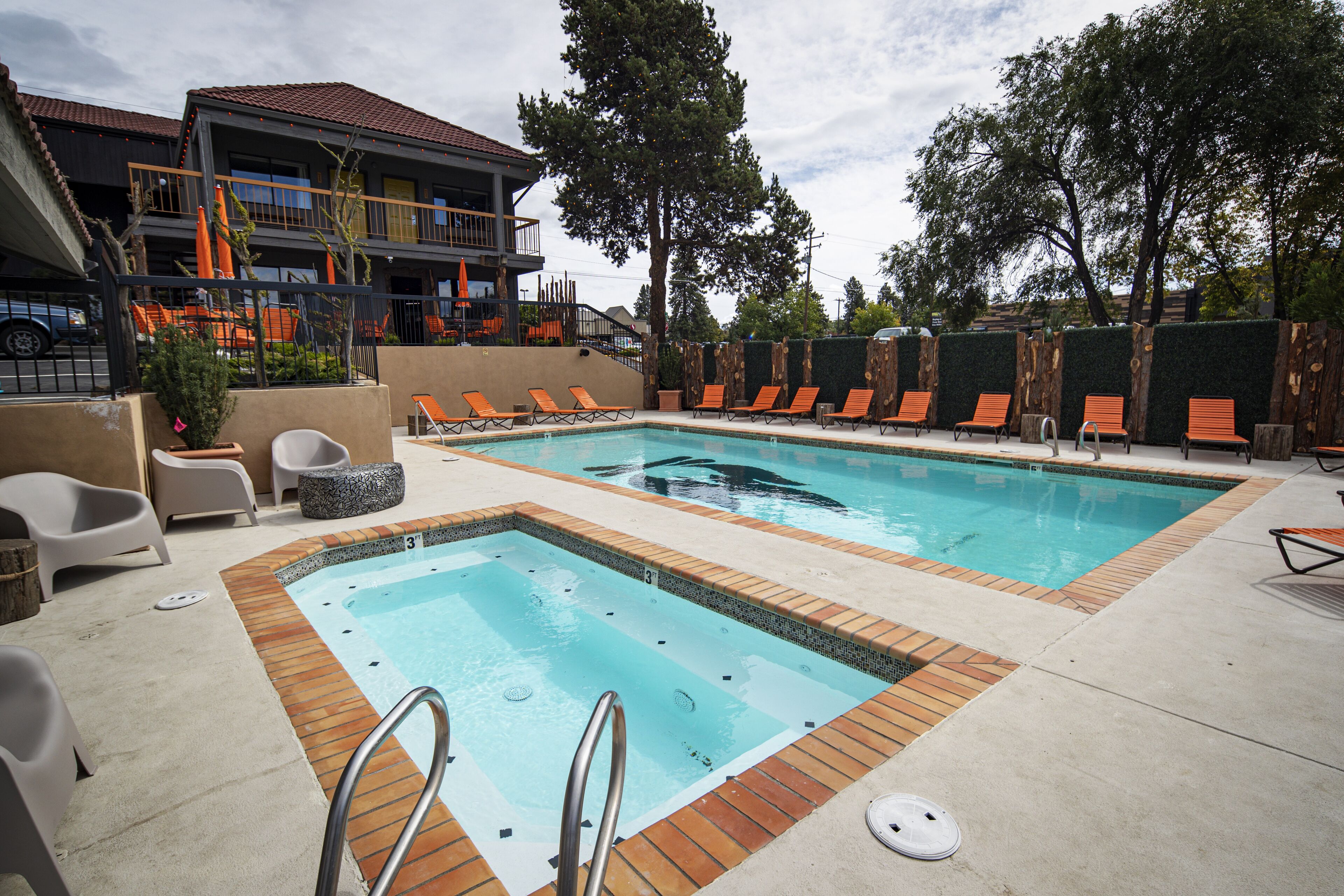 A pool area with lounge chairs, a small pool, and a building with balconies.