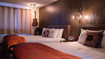 A hotel room with two beds, a guitar, and a wall-mounted light fixture.