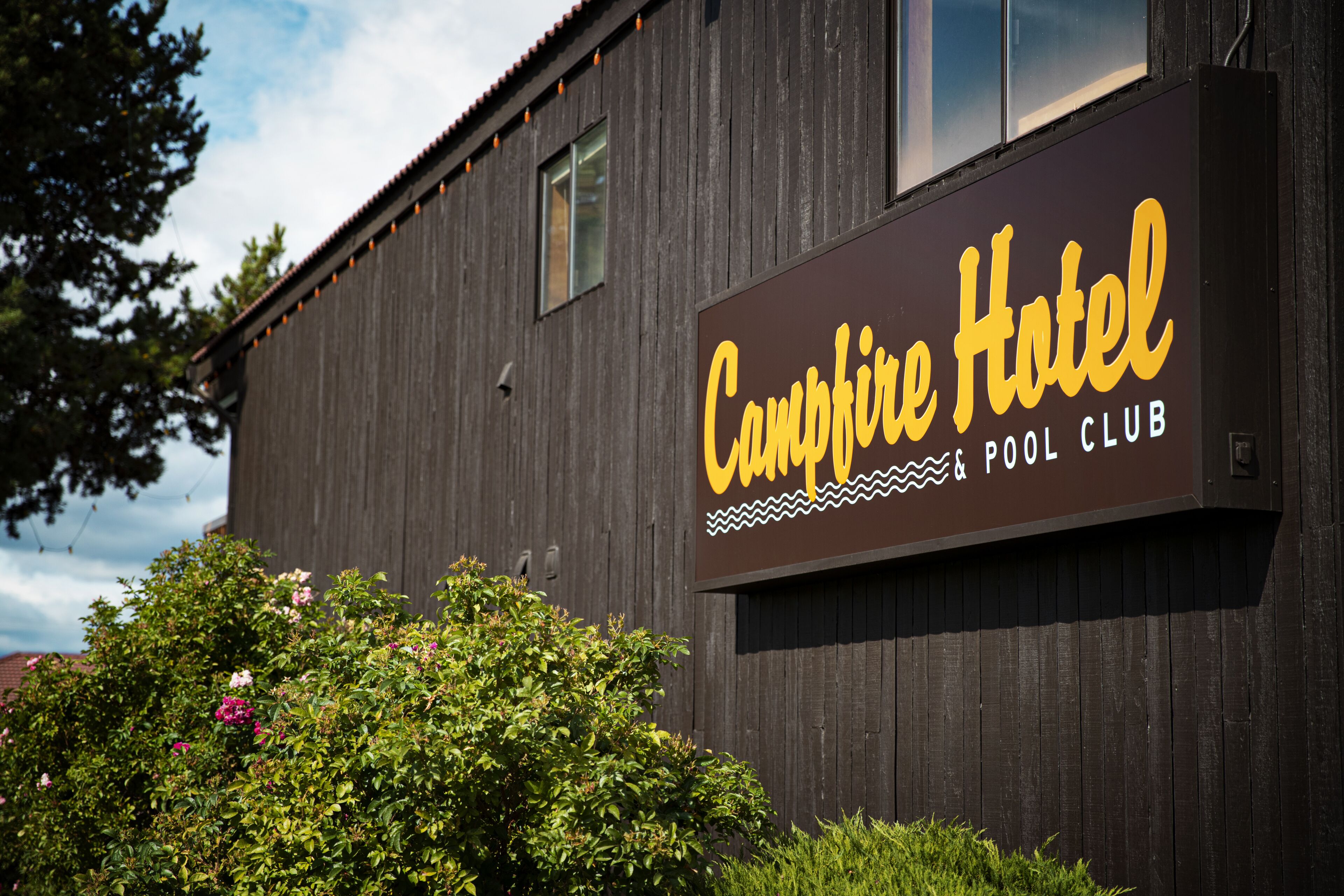 Un edificio in legno con un cartello che riporta la scritta "Campfire Hotel & Pool Club".