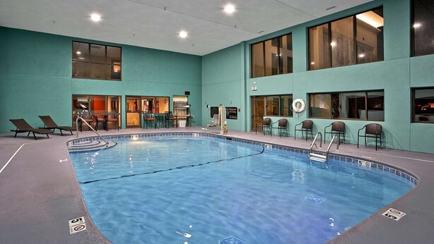 Una piscina interior con agua cristalina, rodeada de sillones de descanso y una terraza con baldosas.