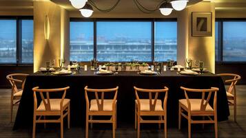 A conference room with a long table, six chairs, and large windows with a city view.