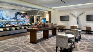 Un hall d’hôtel comprenant un espace buffet, des coins salon et un grand élément décoratif mural.