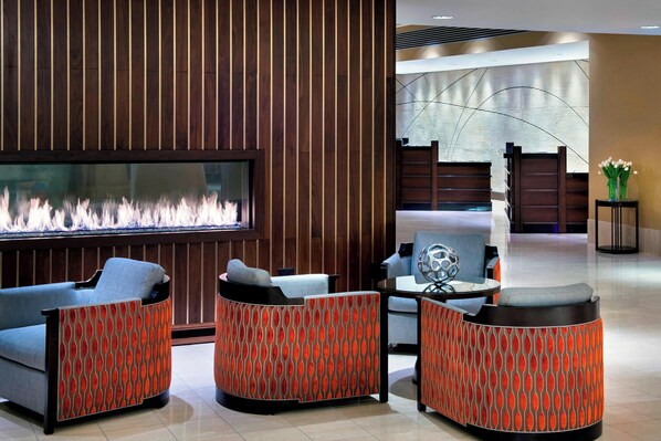 A modern lobby with a fireplace, seating area, and a reception desk.
