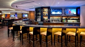Un espace bar moderne doté d’un comptoir incurvé, de nombreux types de sièges et d’une grande variété de bouteilles d’alcool.