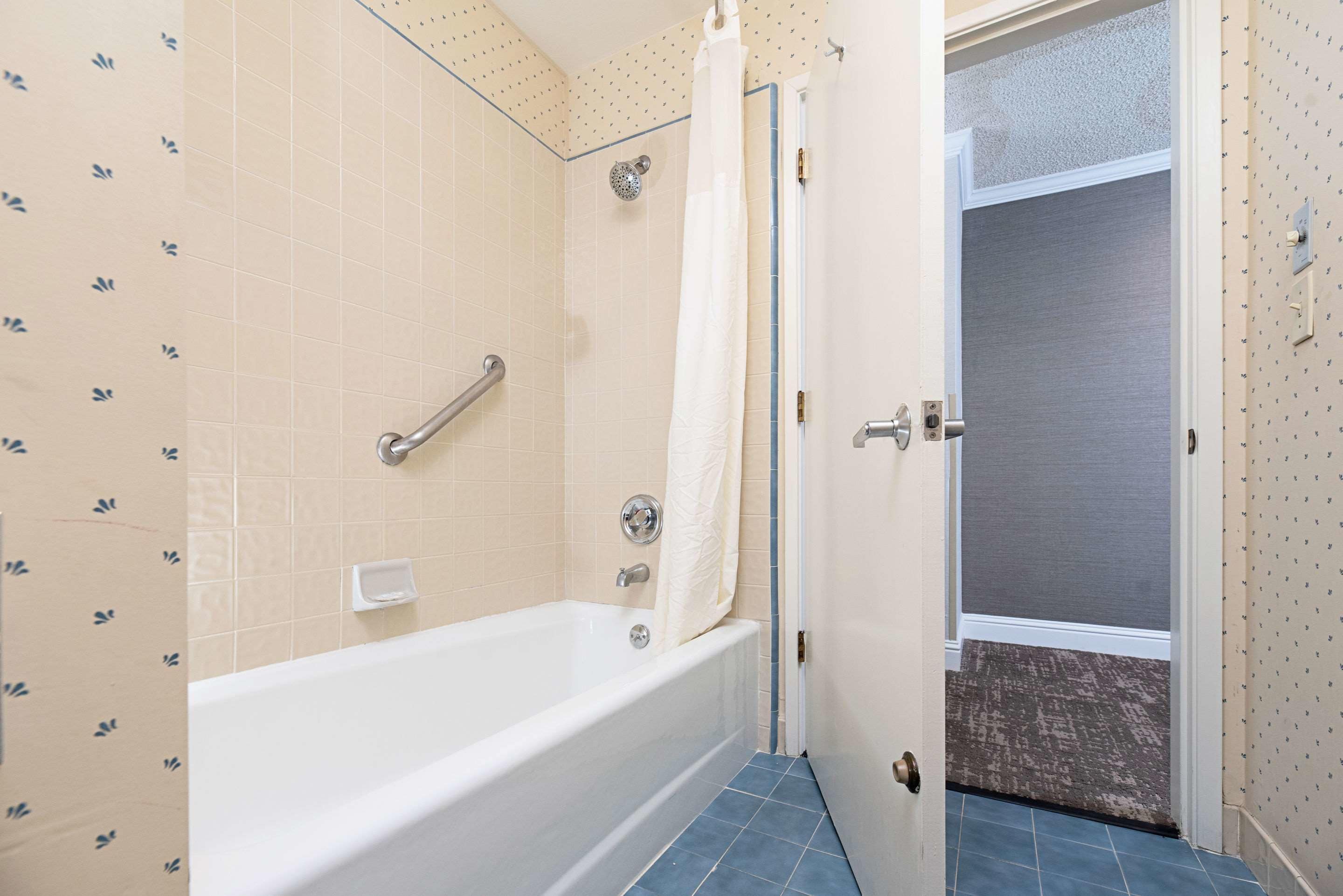 A bathroom with a bathtub, a shower, and a door leading to another room.