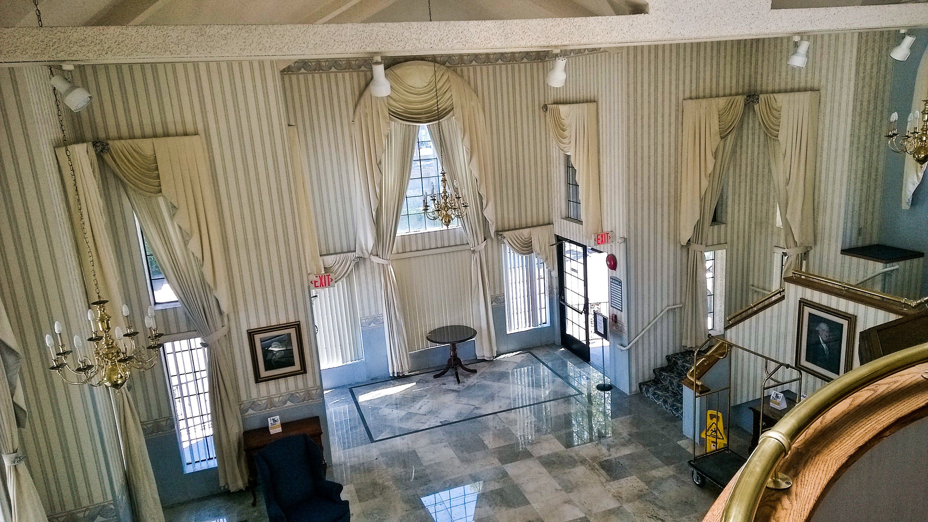 A spacious lobby with high ceilings, striped wallpaper, and a chandelier.