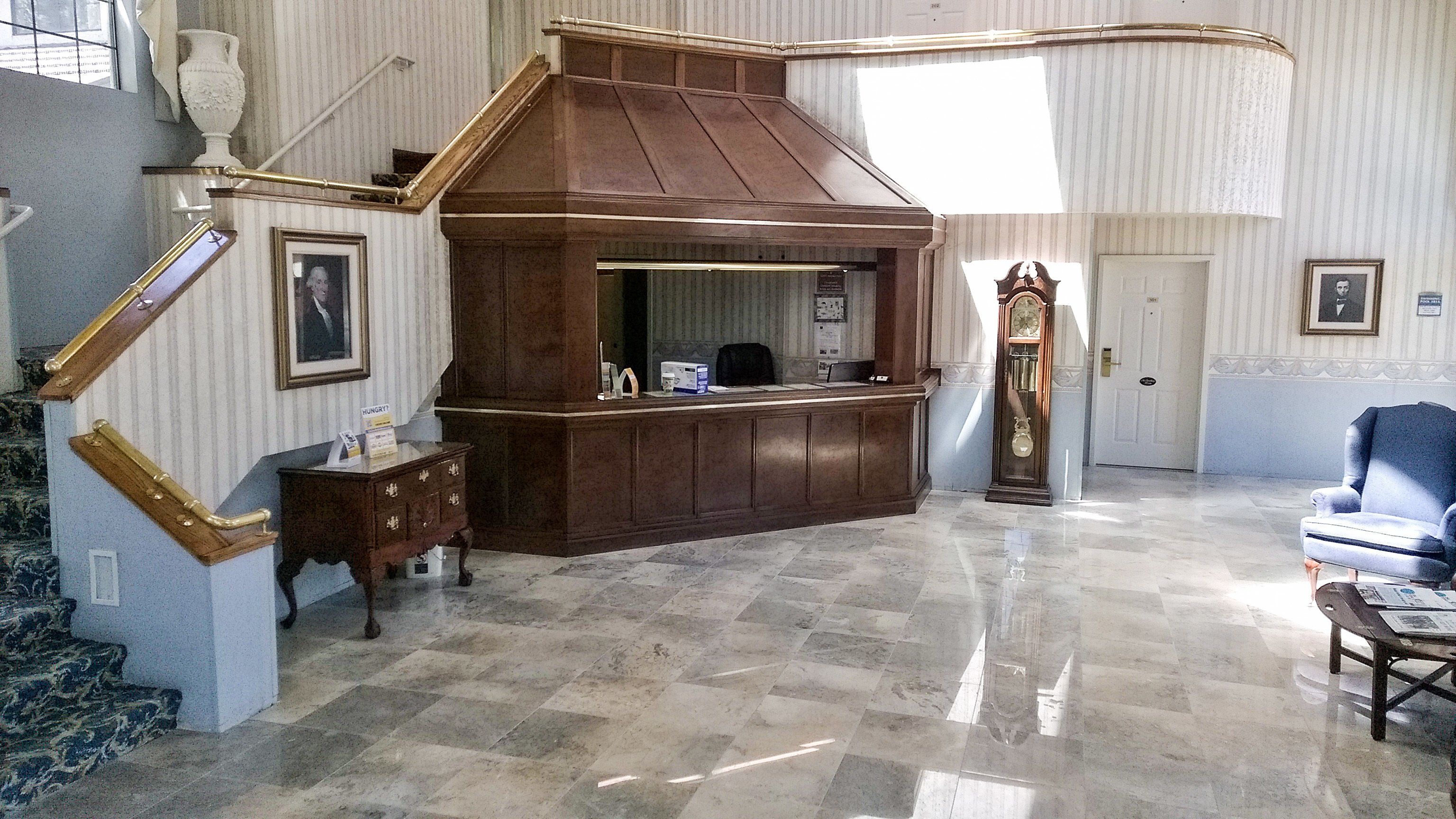 A lobby with a wooden reception desk, a clock, and a blue armchair.