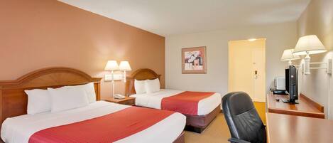 A hotel room with two beds, a desk, a chair, a TV, and a lamp.