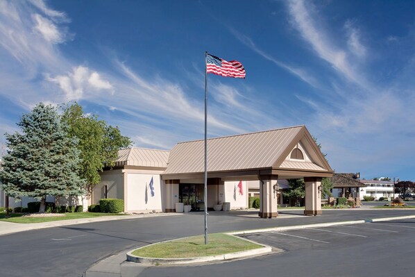 A hotel with a flagpole, a covered entrance, and a parking lot. - Ramada by Wyndham Provo (Provo)