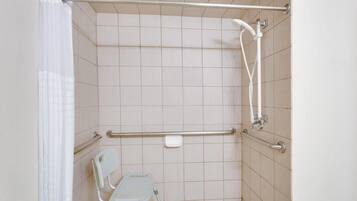 Ein Duschbereich mit Haltegriff, einem weißen Stuhl und einer Handbrause.