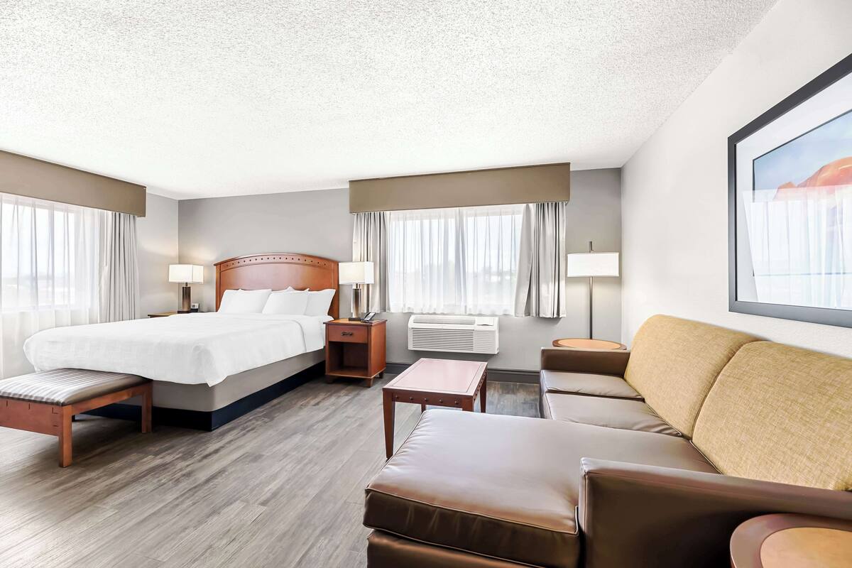 A hotel room with a bed, a sofa, a small table, and a bench.