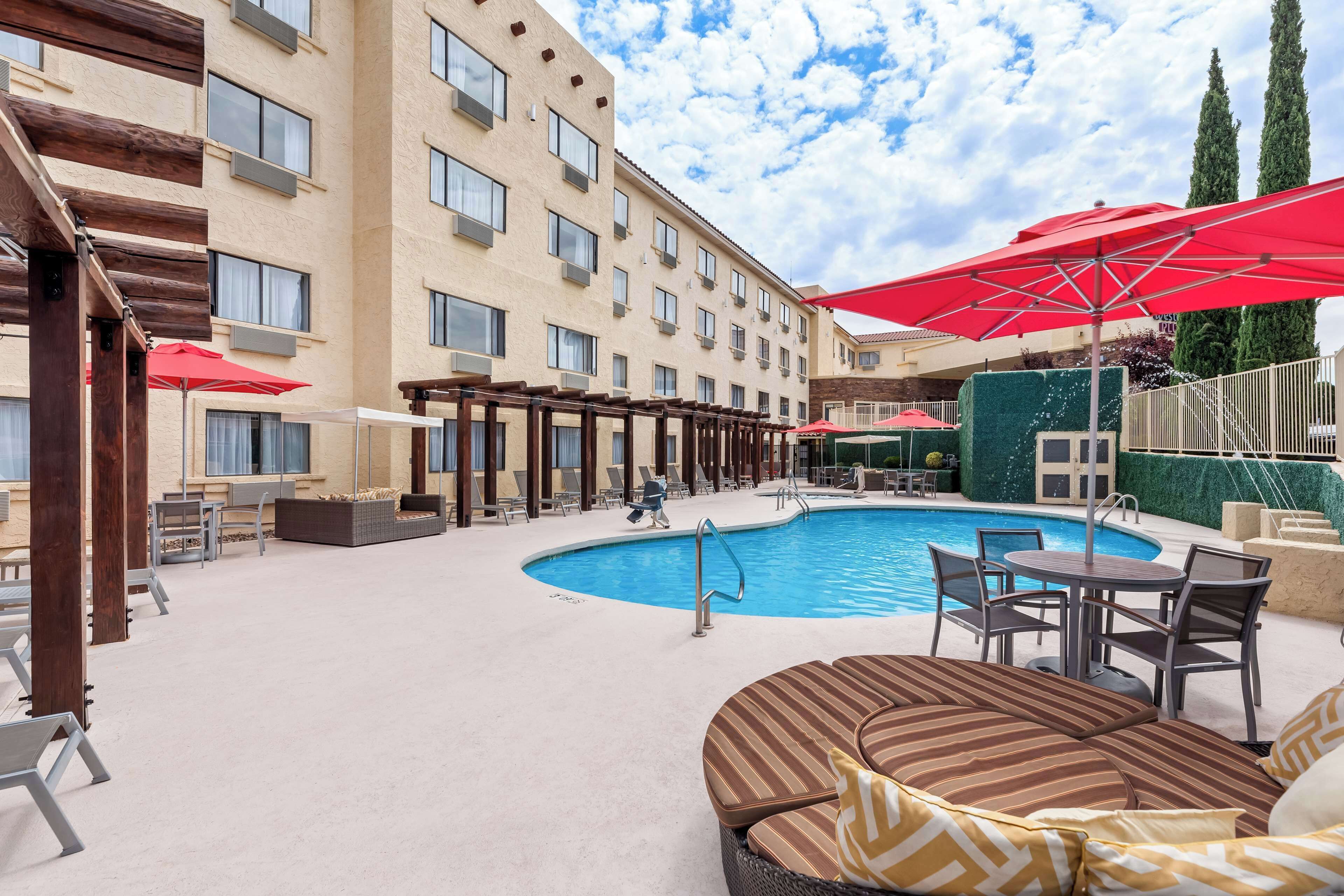 A hotel pool area with a pool, lounge chairs, and umbrellas.