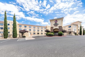 A hotel with a central entrance, multiple floors, and a parking lot.
