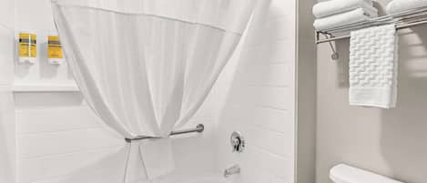 A bathroom with a bathtub, a toilet, and a towel rack with folded towels.