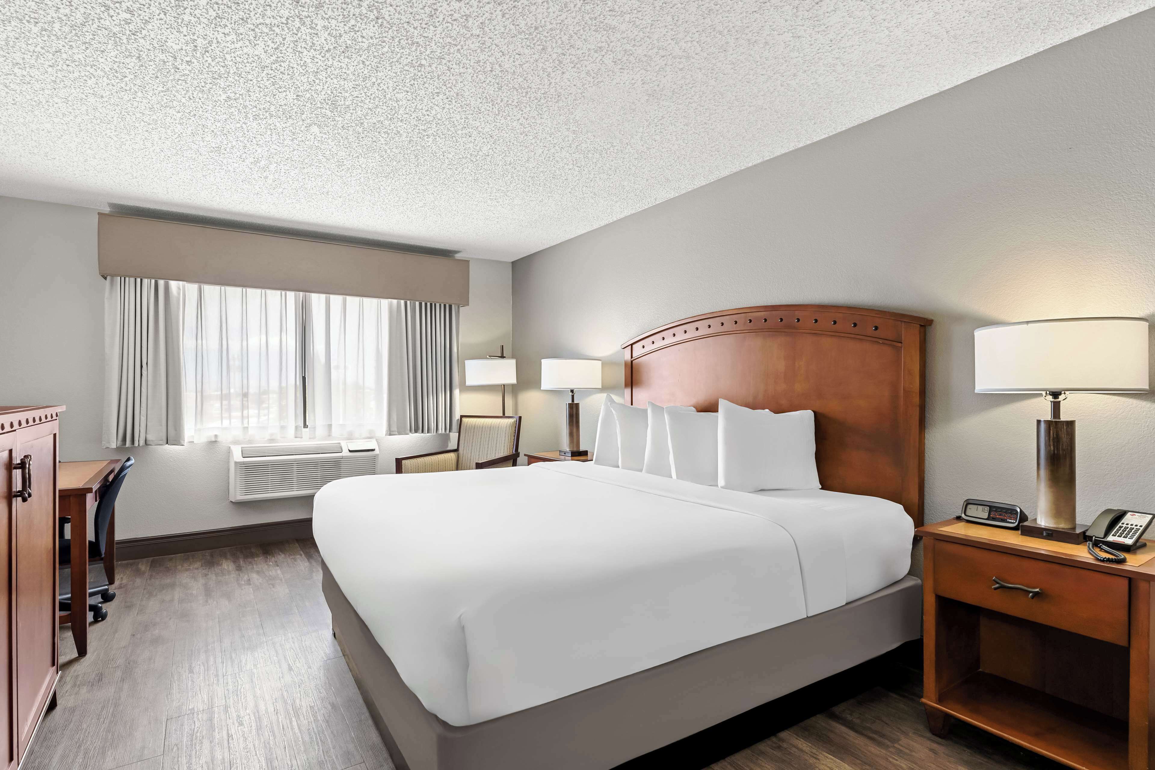 A hotel room with a large bed, bedside lamps, a desk, and a wardrobe.