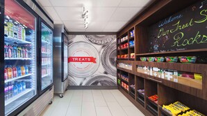 Interior de una tienda con vitrinas refrigeradas para bebidas, un letrero que dice 'Treats' y estantes llenos de bocadillos.