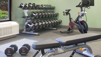 A gym with a bench, dumbbells, and an exercise bike.