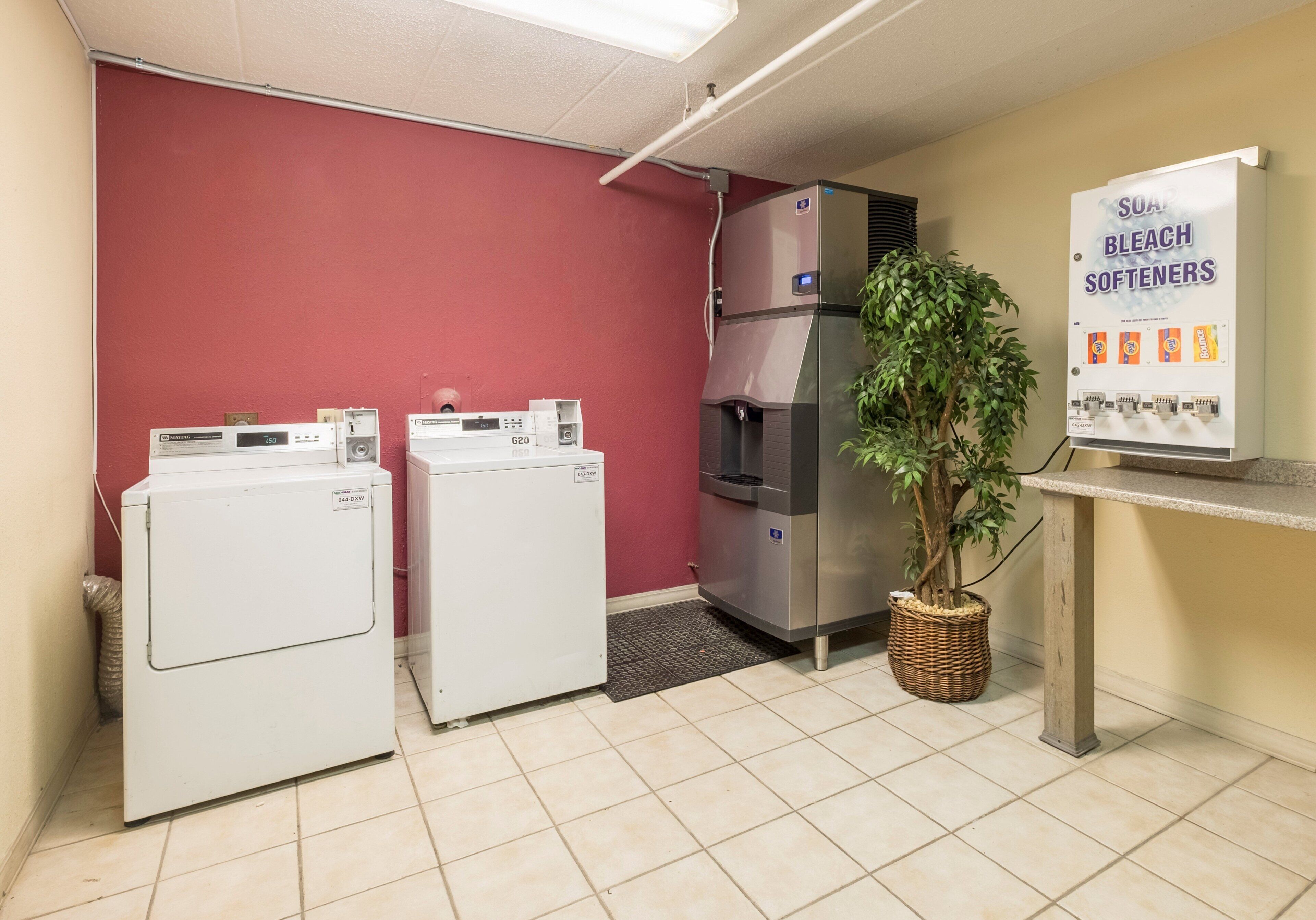 A laundry area with two washing machines, a large refrigerator, and a sign advertising softeners.