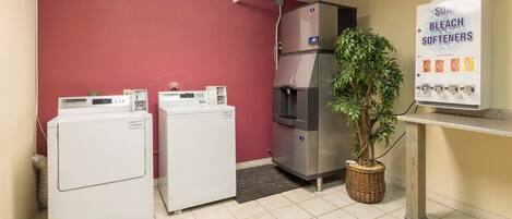 A laundry area with two washing machines, a large refrigerator, and a sign advertising softeners.