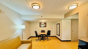 Une salle de conférence avec une table et des chaises, un canapé et une porte.