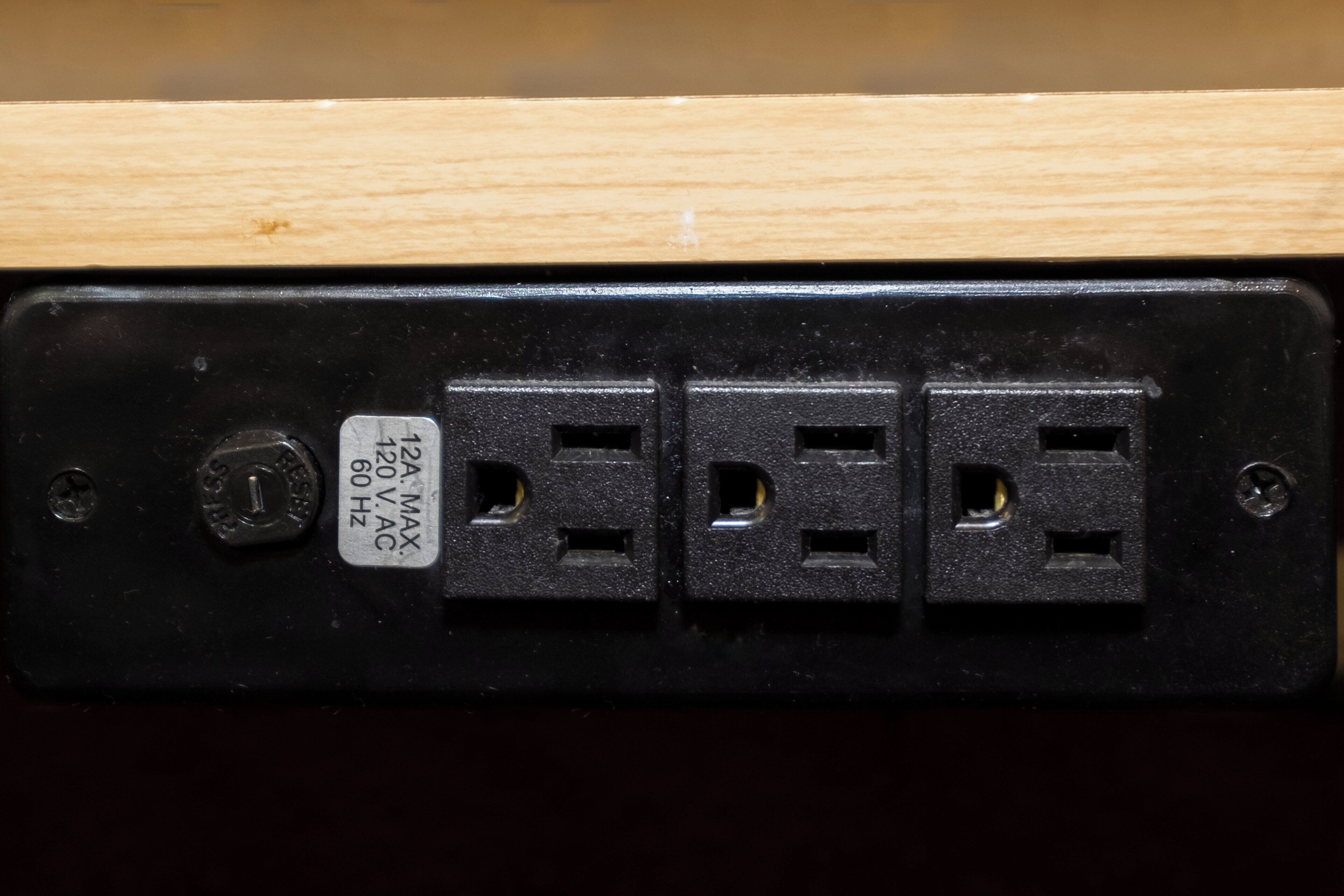 A black electrical outlet with a label indicating a 220V, 60Hz, 2A maximum current rating.
