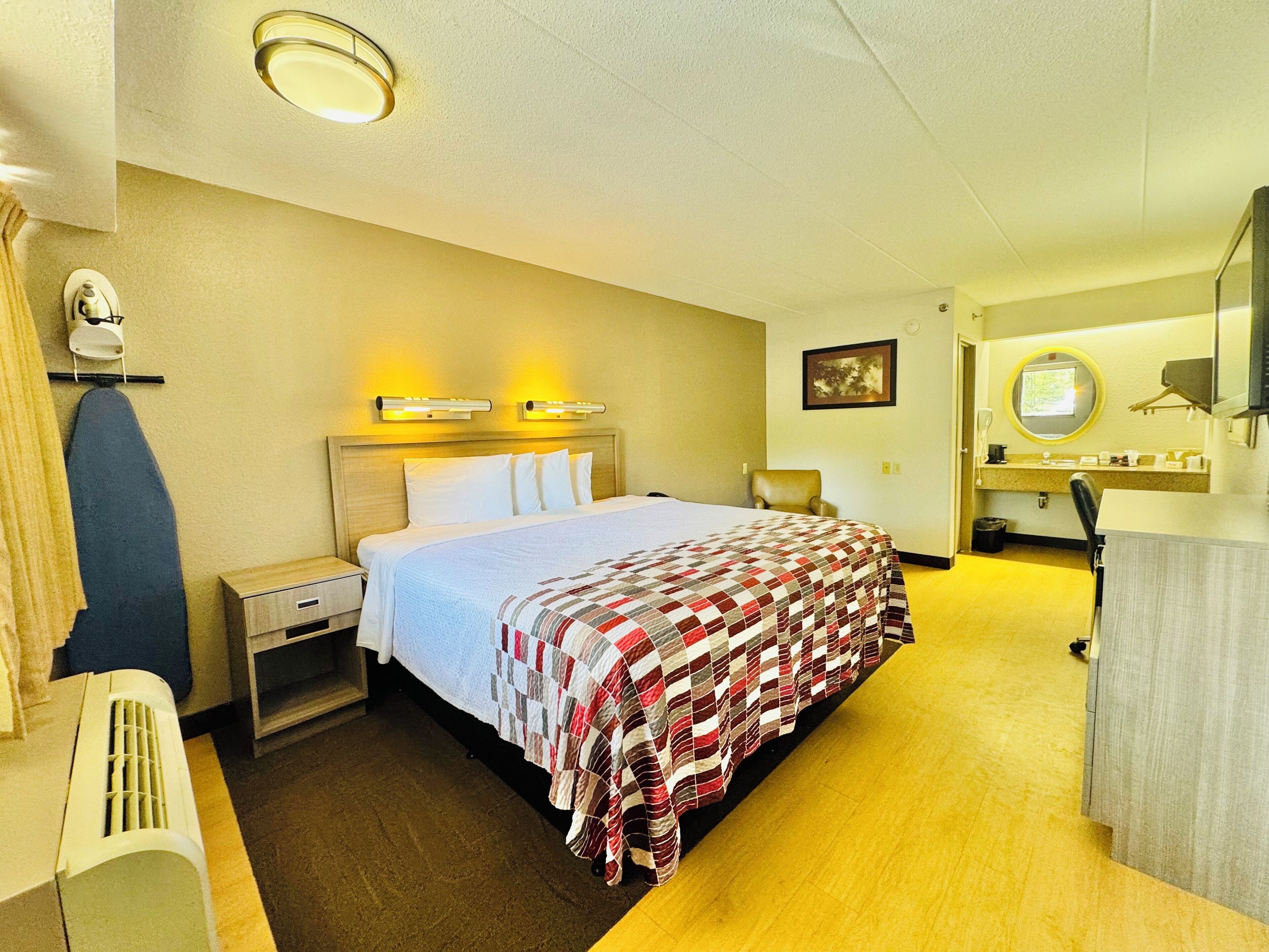A hotel room with a bed, a chair, a desk, and a bathroom.