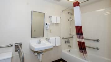 A bathroom with a sink, mirror, towel rack, shower, and a hand dryer.