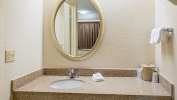 A bathroom with a granite countertop, a sink, a mirror, a towel rack, and a toilet paper holder.