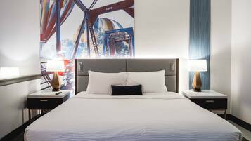 A hotel room with a large bed, two bedside tables with lamps, and a mural of a bridge on the wall.