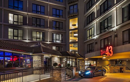 A multi-story hotel with a prominent 'Hotel 43' sign, a stone facade, and a car parked in front.
