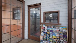 A room with a white brick wall, a wooden door, and a window with a view of a brick building. - Econo Lodge Austin North near The Domain (Austin)