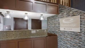 A hotel reception area with a granite counter, three pendant lights, a wall-mounted sign, and a patterned wall. - Econo Lodge Austin North near The Domain (Austin)