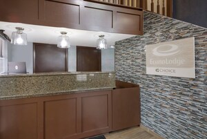 A hotel reception area with a granite counter, three pendant lights, a wall-mounted sign, and a patterned wall.