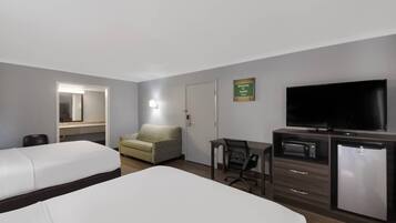 A hotel room with two beds, a desk with a chair, a television, a microwave, and a refrigerator.