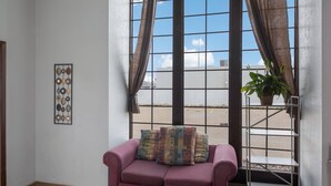 A room with a purple sofa, a potted plant, and a window with curtains. - Econo Lodge Austin North near The Domain (Austin)