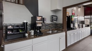 A modern kitchen with a coffee machine, a paper towel dispenser, and a microwave. - Econo Lodge Austin North near The Domain (Austin)