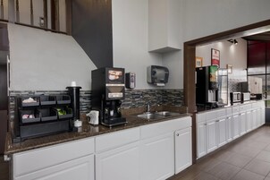 A modern kitchen with a coffee station, a sink, and a refrigerator.