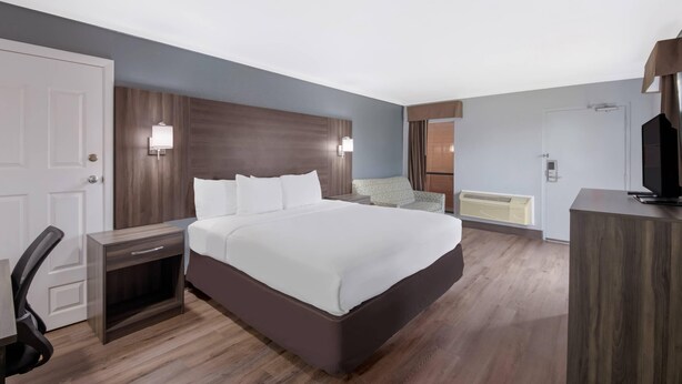 A hotel room with a large bed, bedside tables, a desk, and a chair. - Econo Lodge Austin North near The Domain (Austin)