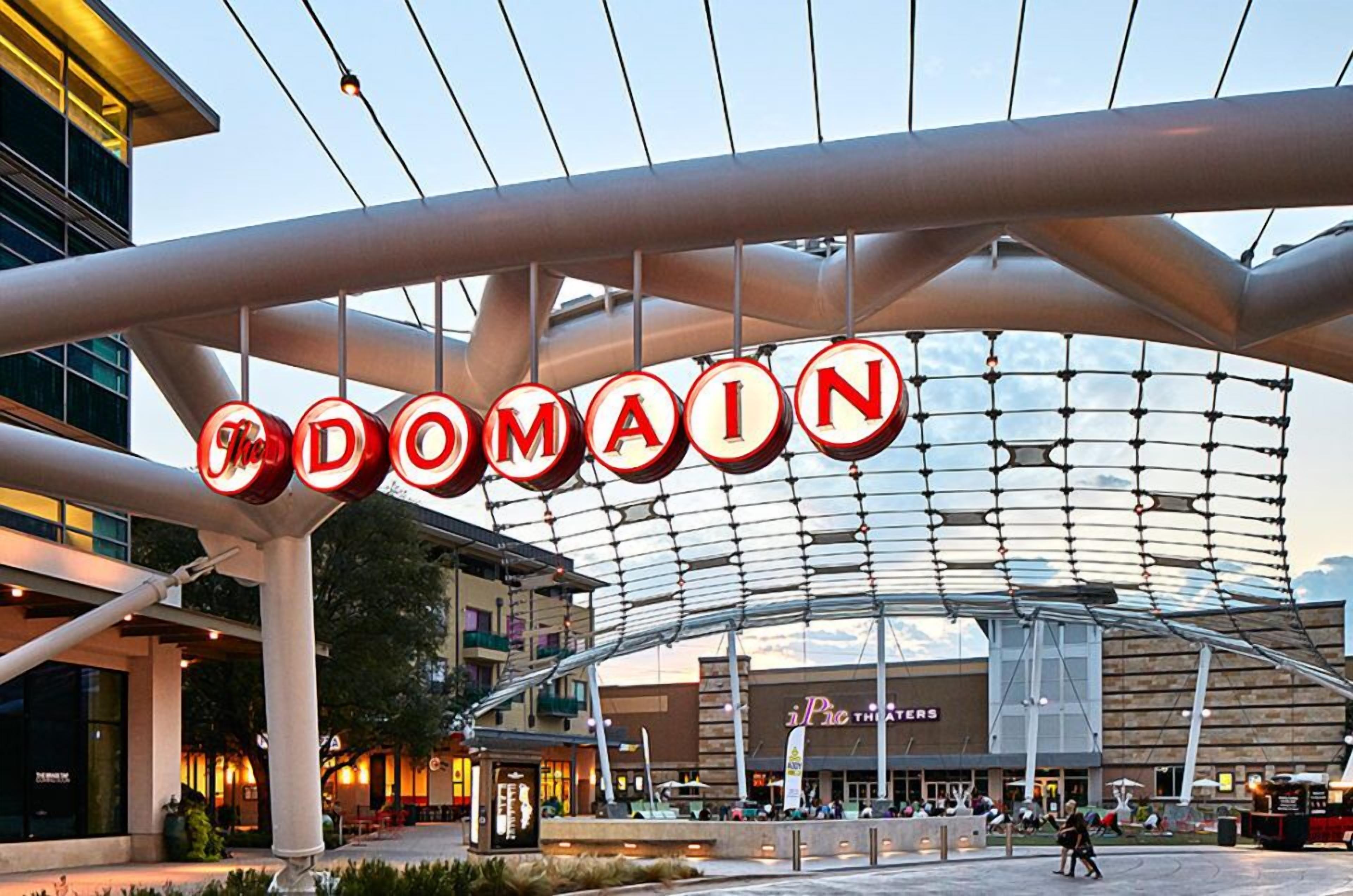 A modern architectural structure with a large sign reading "DOMAIN" above a covered area.