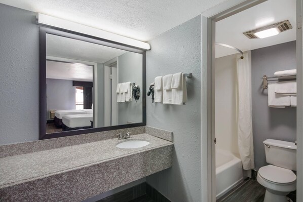 Un baño con lavamanos doble, un espejo grande, ducha e inodoro.