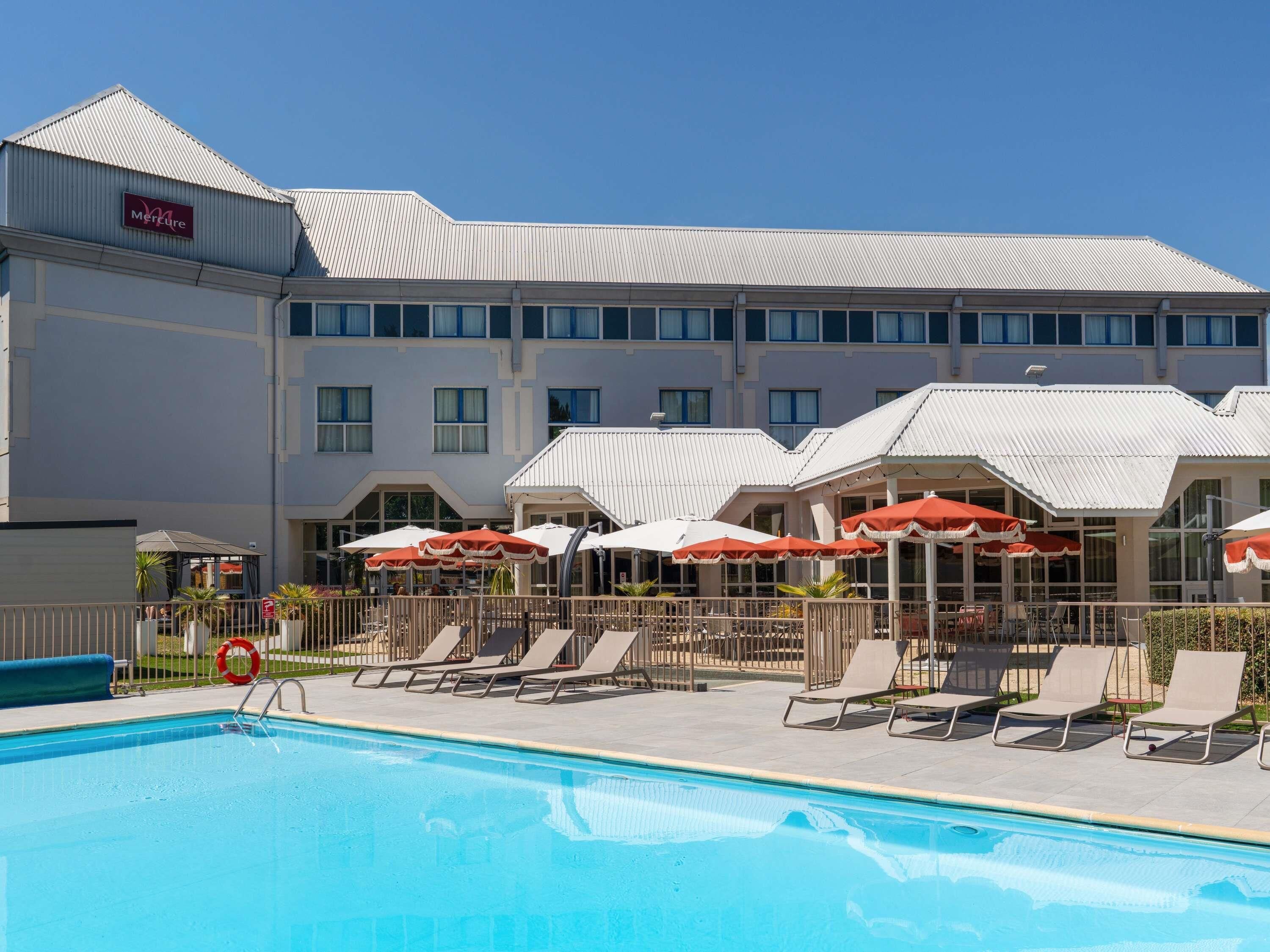 Een hotel met een zwembad, ligbedden en parasols.