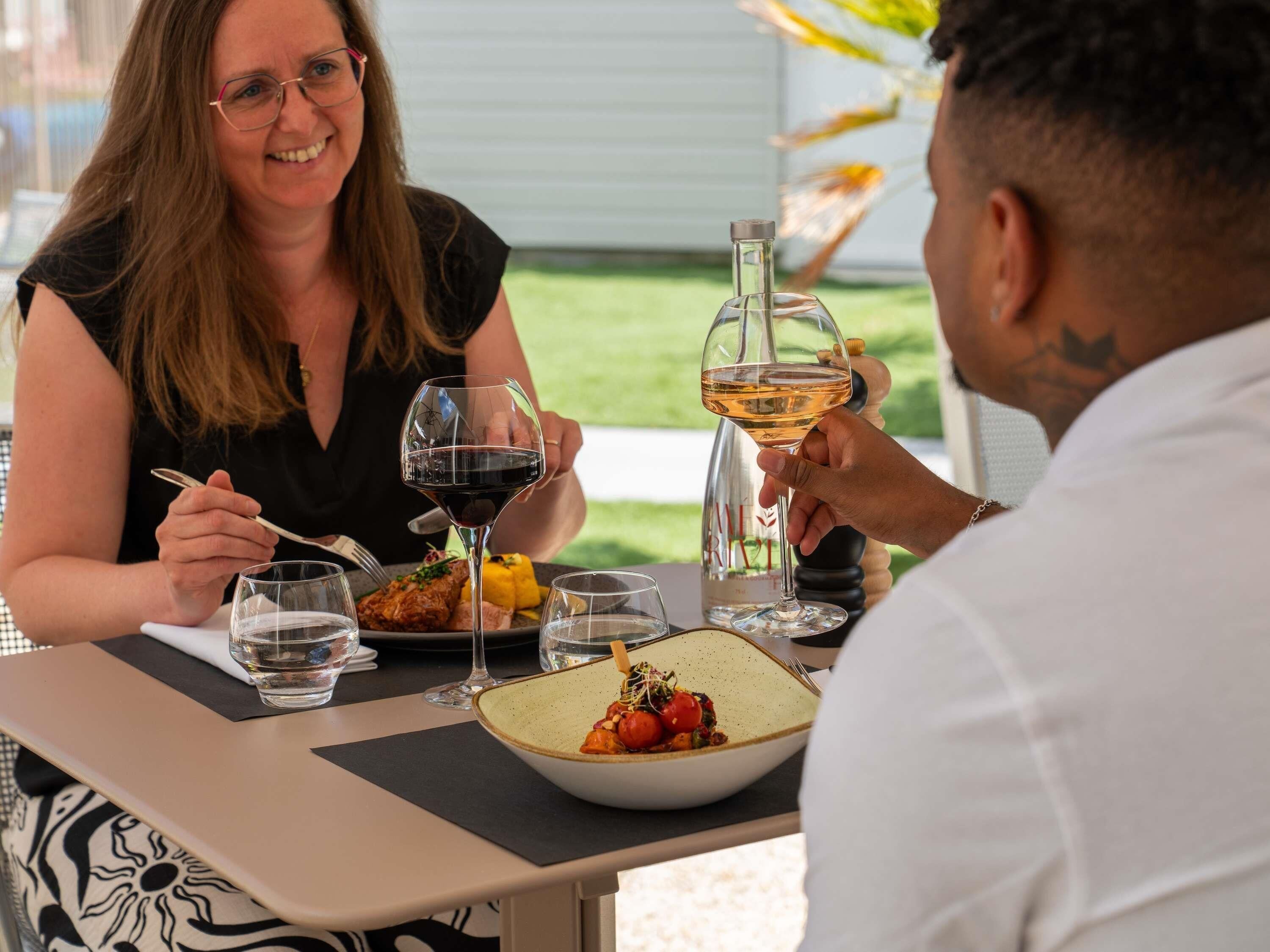 Une table à manger avec une bouteille de vin, des verres et une assiette de nourriture.