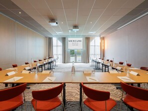 Un salón de conferencias con una larga mesa, sillas rojas, tarjetas de identificación y un letrero que dice 'Mercure Hotels Tours Nord'.