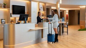 Un mostrador de recepción de hotel con un televisor de pantalla plana, un quiosco digital y una barra de recepción.
