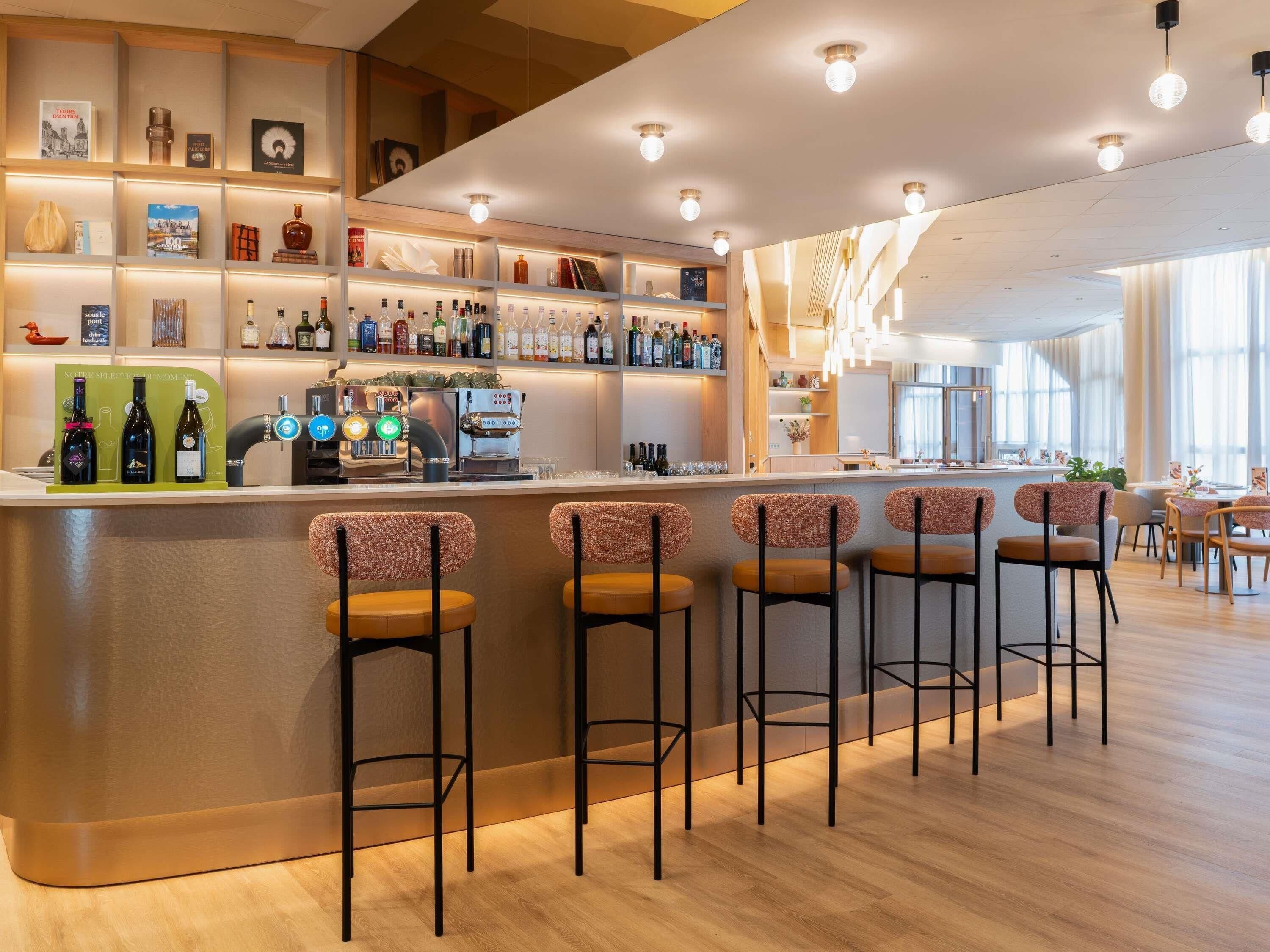 Eine Bar mit Theke, Barhocker und Regalen voller Flaschen.