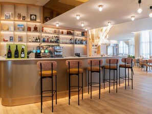 A bar area with a counter, bar stools, and shelves with bottles.