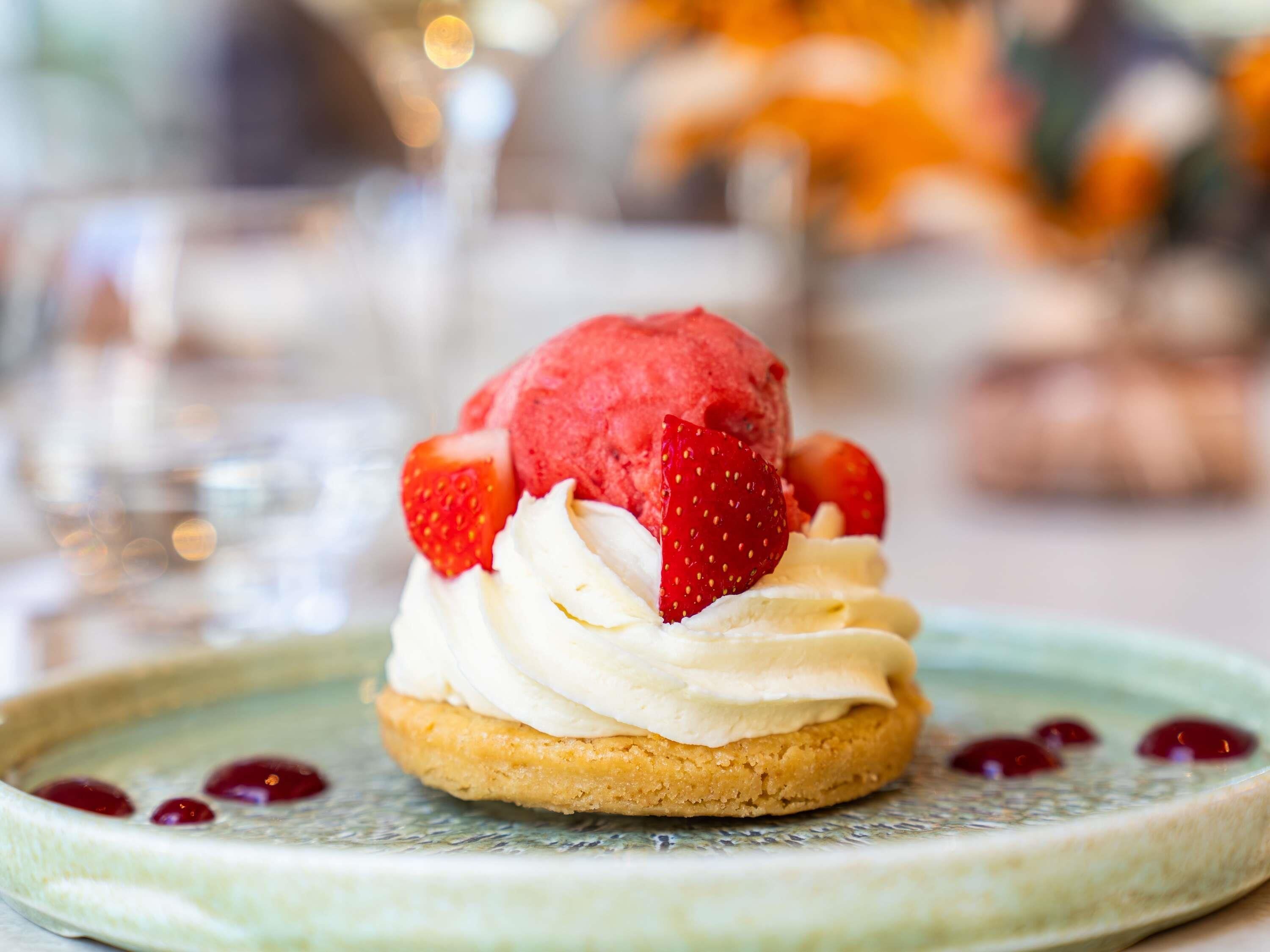 A dessert with a scoop of ice cream, strawberries, and whipped cream on a biscuit.