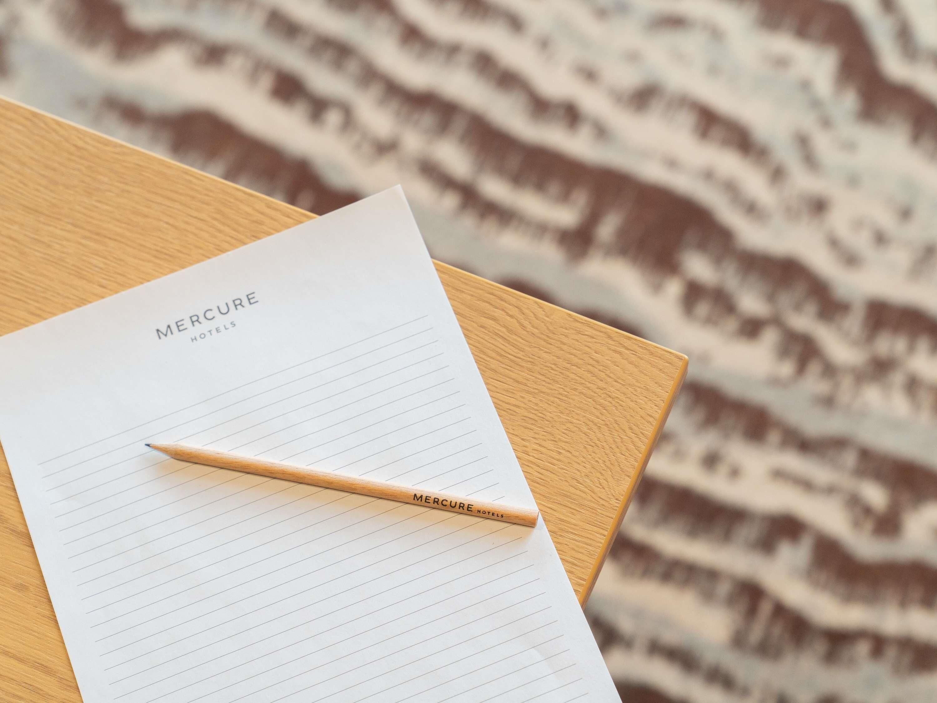 A lined notepad with 'Mercure Hotels' printed on it, placed on a wooden surface.
